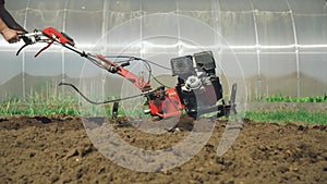 Modern agriculture. Farmer worker plows the soil with a motor cultivator, tiller tractor, farming