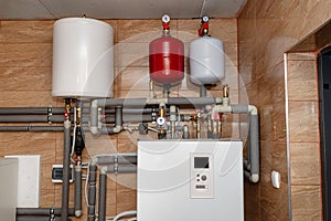 A modern air heat pump installed in the home\'s boiler room, visible plastic pipes and valves.