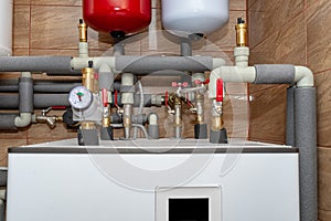 A modern air heat pump installed in the home\'s boiler room, visible plastic pipes and valves.