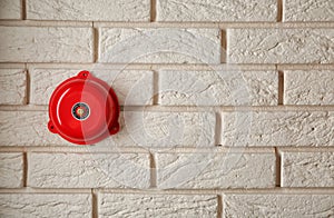 Modern alarm bell on brick wall indoors