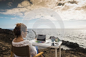 Modern and alternative lifestyle office wokstation with free business woman at work in open office with scenic ocean view -