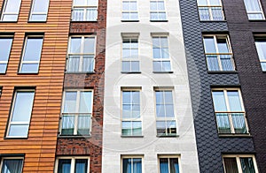 Modern apartment building exterior facade with lot of different materials: wood, stone bricks.