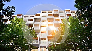 Modern apartment building and green trees. Ecological housing architecture.