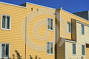 Modern apartment building with orange and wooden slat and pannel house with building facade exterior in late afternoon