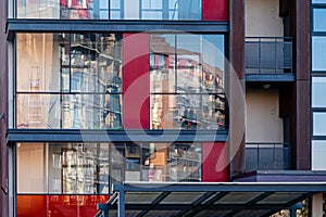 Modern apartment building wall with large windows close-up, reflections in the glass