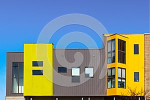 Modern apartment or office builing with clean lines and bright colored and metal siding blocks against very blue sky