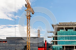 Modern apartment residential building glass facade wall construction site with many high tower cranes and heavy