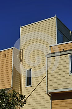 Modern appatment building with beige horizontal wooden slats in late afternoon sun and shade with dark blue sky