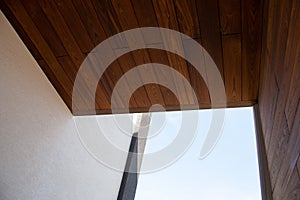 Modern architecture detail of wooden facade cladding, white wall and sky background