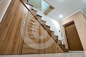 Modern architecture interior with luxury hallway with glossy wooden stairs in multi-storey house. Custom built pullout cabinets on