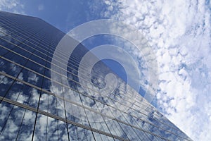 Modern architecture, panoramic view of beautiful reflecting glass wall with blue sky and clouds