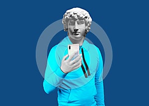Modern art collage. Concept portrait of a man holding mobile smartphone using app texting sms message. Gypsum head of Antinous. photo