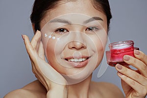 Modern asian female with facial cream jar