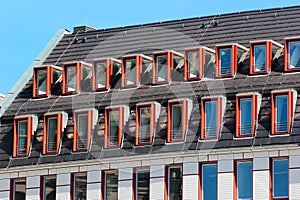 Modern attic windows on roofs against blue sky background