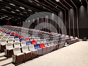 Modern auditorium, cinema hall or movie theater with rows of red, blue, black, gray or grey and white seats or chairs