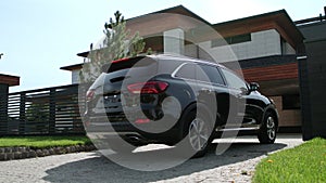 Modern auto driving to luxury house. Closeup black jeep entering luxury garage.