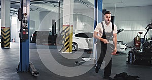 Modern auto garage young mechanic dancing excited at workout while fixing the car , he have a good mood and great day at