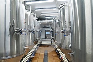 Modern automated beer factory. Lines of metal tanks in modern brewery. Shopfloor with brewery facilities. Manufacturable process o
