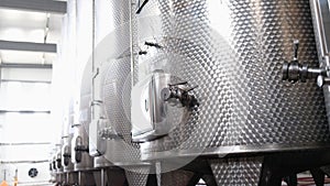 Modern automated winery with lines of metal tanks. Interior view of modern brewery with stainless steel barrels