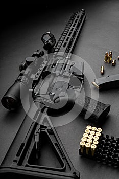 Modern automatic carbine with optical and collimator sight. A rifle with two sights on a dark background. Cartridges for weapons photo