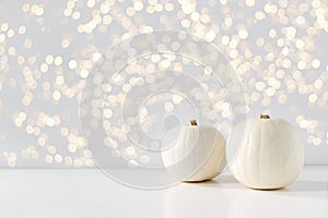 Modern autumn styled composition with white pumkins and golden sparkling bokeh lights. Halloween, Thanksgiving party