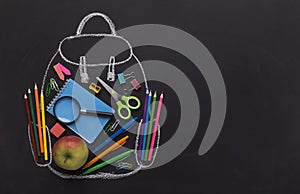 Modern backpack with school stationery inside on black board