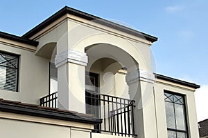 Modern balcony of a two-story house in light-colored plaster