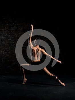 Modern ballet dancer in black shorts performing art jump with empty black copy space background, izolated