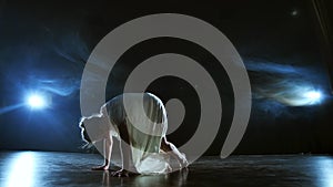 Modern ballet dancing woman barefoot lying on the floor doing spins and pirouettes and somersaults