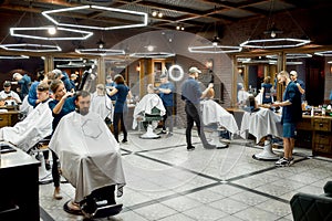 Modern barbershop. Professional barbers serving clients in the modern loft style barber shop. General view. Hairdresser