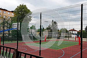 Modern basketball court in the courtyard of primary school. Multifunctional children`s playground with artificial surfaced fenced