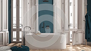 Modern bathroom in blue tones in classic apartment with window with shutters and parquet. Freestanding bathtub, pouf with