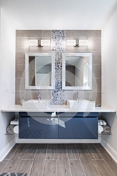 A modern bathroom with a blue vanity and rock back splash.