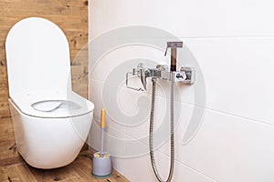 Modern bathroom. Close-up of white toilet bowl and a hygienic shower on the wall