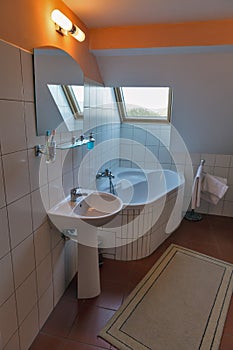 Modern bathroom with corner bath, washbasin and window.