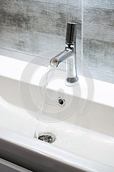 Modern bathroom faucet. Flowing water from water tap, copy space