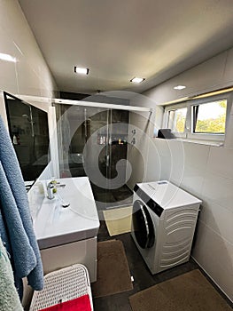 Modern bathroom with glass shower and washing machine in a compact, tidy space