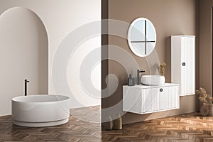 Modern bathroom interior with beige walls, white basin with oval mirror, bathtub and parquet floor.