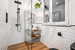 Modern bathroom interior with black shower, round mirror and classic white tiles