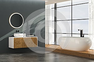 Modern bathroom interior with concrete flooring, white bathtub and white oval sink, front view.