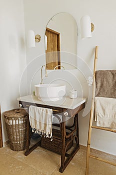 Modern bathroom interior. Modern ceramic sink with golden faucet on rustic stand with soap and towel on background of wall with