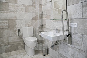 modern bathroom interior with white toilet, handicapped rails, white sink and mirror