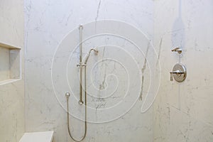 In the modern bathroom of a new construction, there is a shower head in front of the tub