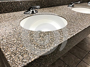Modern bathroom with quartz countertop, two sinks and faucets with stone floor