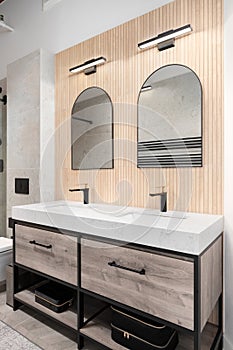 A modern bathroom with a wood slat wall and arched mirrors. photo