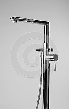 Modern bathtub faucet with hand shower on grey background