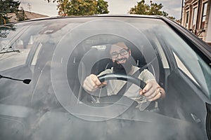 A modern bearded man driving a car