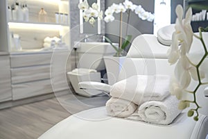 Modern beauty salon interior with a comfortable white chair, clean towels, and orchid plant, with a serene atmosphere