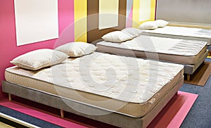 Modern bed with mattresses and pillows in store