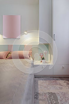 A modern bedroom in blue, pink and white colors with muffled lighting. Real photo